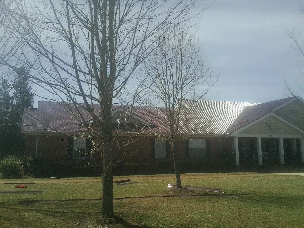 Red metal roof on a brick building seen from the front lawn in Elko