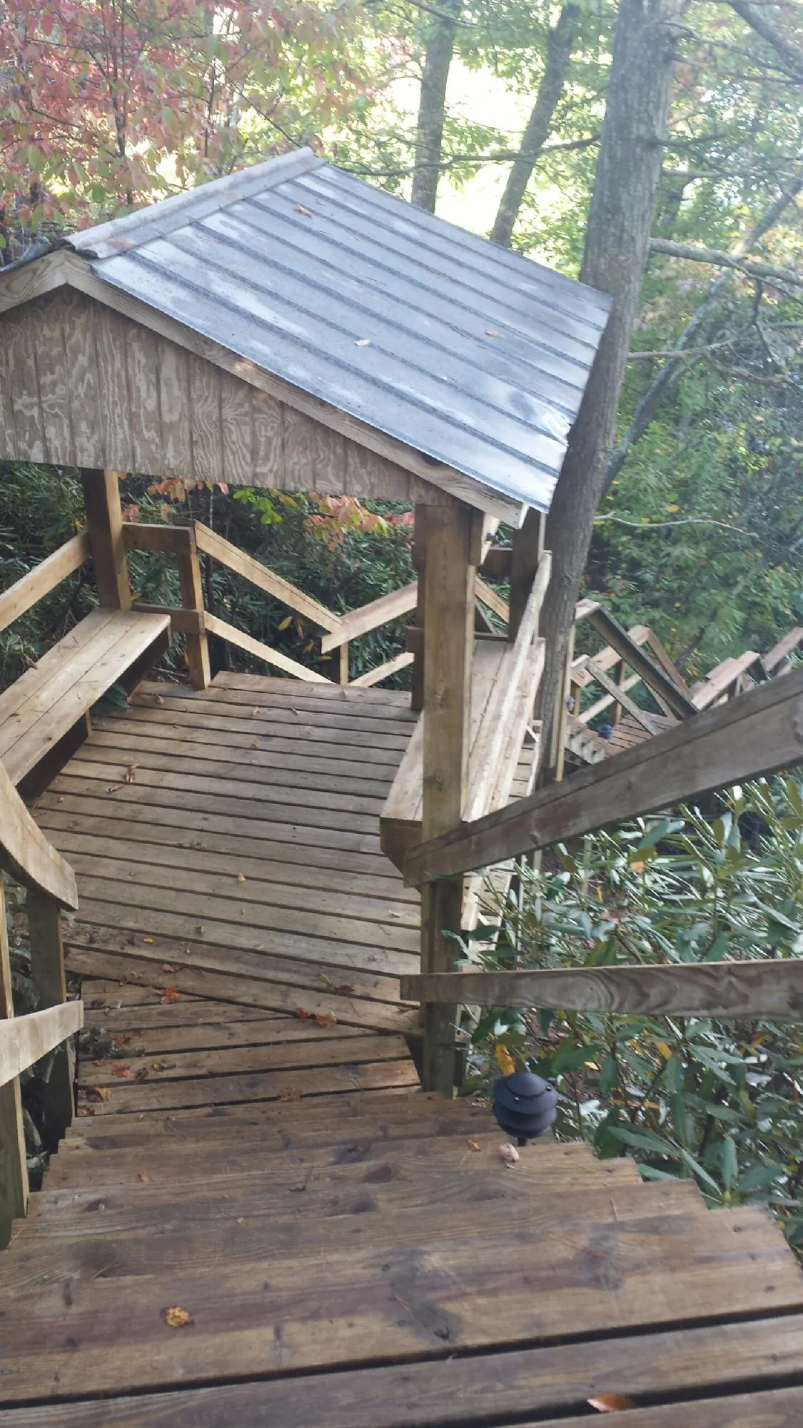 Metal roofed shelter over wooden steps on a wooded walkway — Skylight Repair & Installation work by our crew in Elko