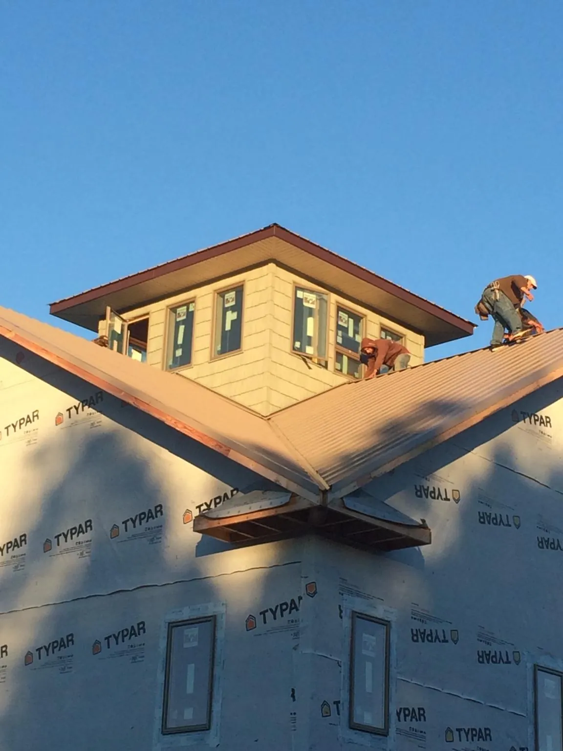 Roofers working around a rooftop cupola on a new metal roof at sunset — Roof Waterproofing in Elko by Roofing Brothers